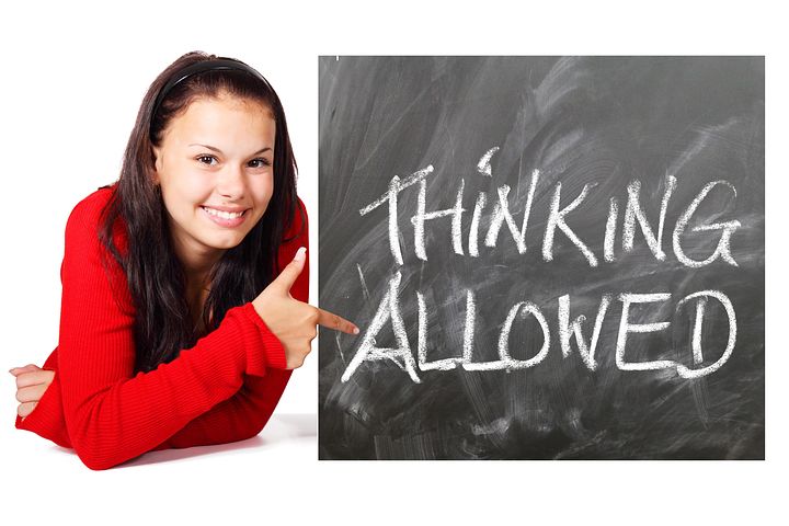 young girl pointing 'Thinking Allowed' written in black board