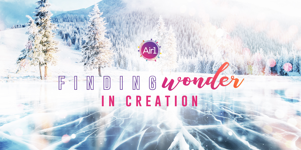 Frozen lake and snow covered tree-filled mountain. Air1 Christmas logo. "Finding Wonder in Creation"