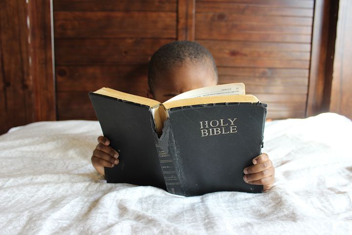 Kid carrying and reading Bible 