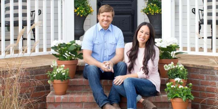 Chip and Joanna smiling in-front of a home