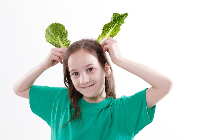 girl holding two green leafs as ears