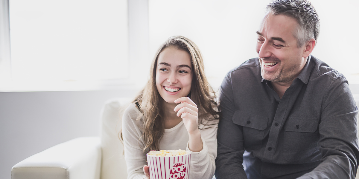 Father and Daughter smiling with popcorn on hand