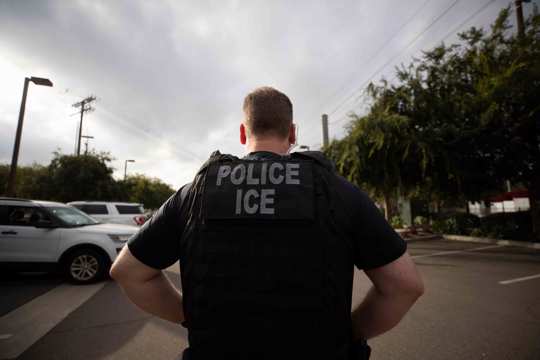 U.S. Immigration and Customs Enforcement (ICE) officer looks on during an operation in Escondido, California