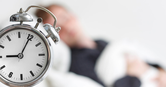 Man sleeping with alarm clock by bedside