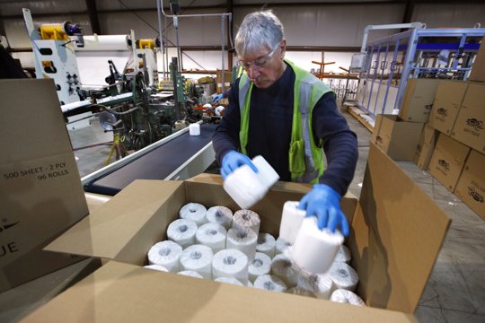 Worker fills box with toilet paper
