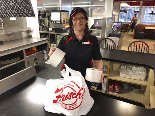 Frisch's Big Boy restaurant employee Nicole Cox bags up an order of toilet paper, among in-demand items including milk and bread the double-decker burger chain is now offering during the coronavirus outbreak in Cincinnati