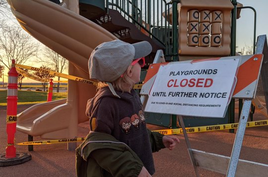 child looks at closed playground