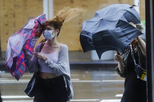 Pedestrians struggle to control their umbrellas due to inclement weather brought about by Tropical Storm Fay, Friday, July 10, 2020, in New York. Beaches closed in Delaware and rain lashed the New Jersey shore as fast-moving Tropical Storm Fay churned north on a path expected to soak the New York City region.