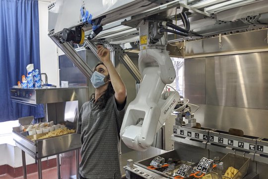 Technician makes an adjustment to a robot at Miso Robotics' White Castle test kitchen in Pasadena, Calif.