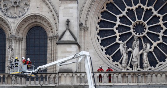 Workers sit on scaffolding at Notre Dame Cathedral