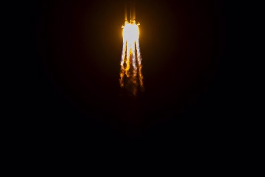 rocket lifts off, exhaust and flames trail behind