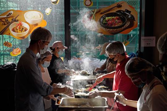 workers prepare lunch boxes for low-income and people who are homeless