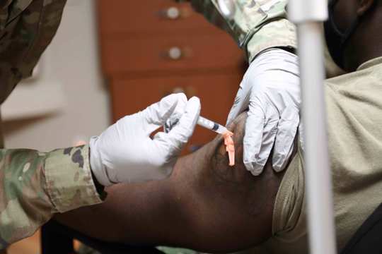 In this photo provided by United States Forces Korea, Sgt. Parmer Smith, 129 medical detachment, administers one of the first COVID-19 vaccines to Navy Petty Officer 2nd Class John London, a Hospital Corpsman, SOCKOR Medics, at Brian D. Allgood Army Community Hospital at U.S. Army Garrison Humphreys, in Pyeongtaek, South Korea Tuesday, Dec. 29, 2020.