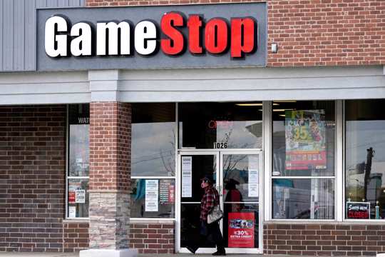 A woman wears a face mask as she walks past a GameStop store in Des Plaines, Ill., Thursday, Oct. 15, 2020.