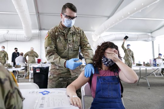 Leanne Montenegro, 21, covers her eyes as she doesn't like the sight of needles, while she receives the Pfizer COVID-19 vaccine at a FEMA vaccination center at Miami Dade College