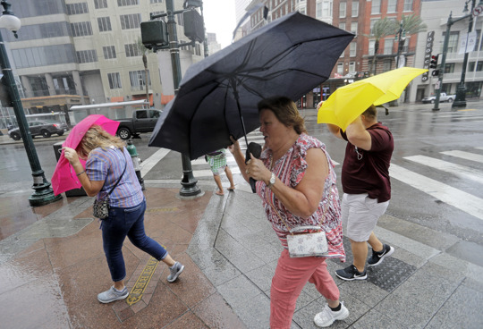 Martha Young, center, Patricia Plishka, left, and her husband Glen, right, battle the wind and rain from Hurricane Barry