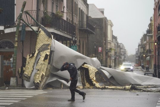 Man passes by a section of roof blown off in New Orleans from Hurricane Ida 