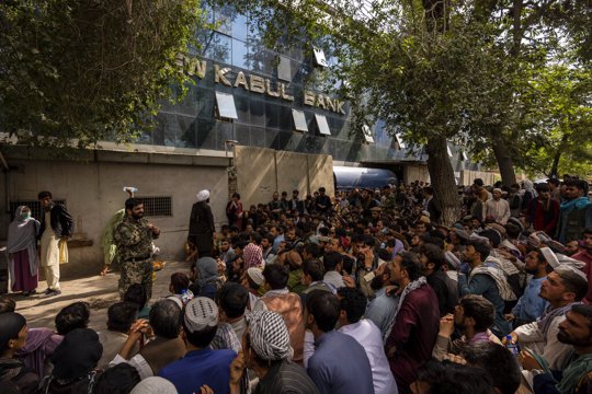 Afghans wait in front of a bank as they try to withdraw money in Kabul