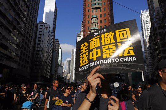 Protesters march with a card that reads "Fully withdraw the extradition to China evil law" in Hong Kong on Sunday, July 21, 2019. Tens of thousands of Hong Kong protesters marched from a public park to call for an independent investigation into police tactics.