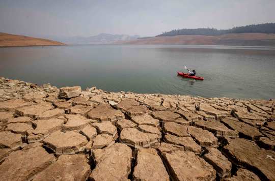 A kayaker fishes in Lake Oroville as water levels remain low due to continuing drought conditions in Oroville, Calif.