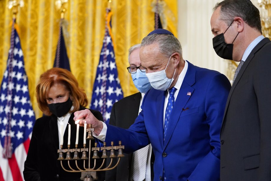 Senate Majority Leader Chuck Schumer of N.Y., second from right, lights the menorah in the East Room of the White House
