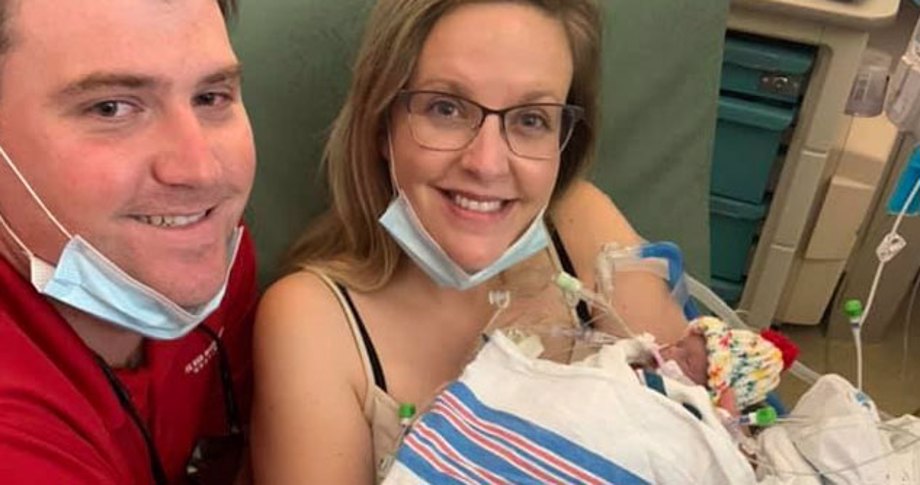 Mom holding premature baby with husband in hospital