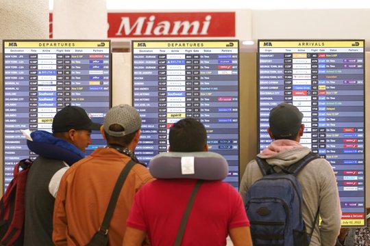 Travelers check their flights at Miami International Airport, Saturday, July 2, 2022, in Miami. The Fourth of July holiday weekend is jamming U.S. airports with the biggest crowds since the pandemic began in 2020.