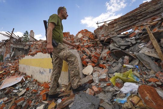 A Ukrainian serviceman looks at the rubble of a school that was destroyed some days ago during a missile strike in outskirts of Kharkiv