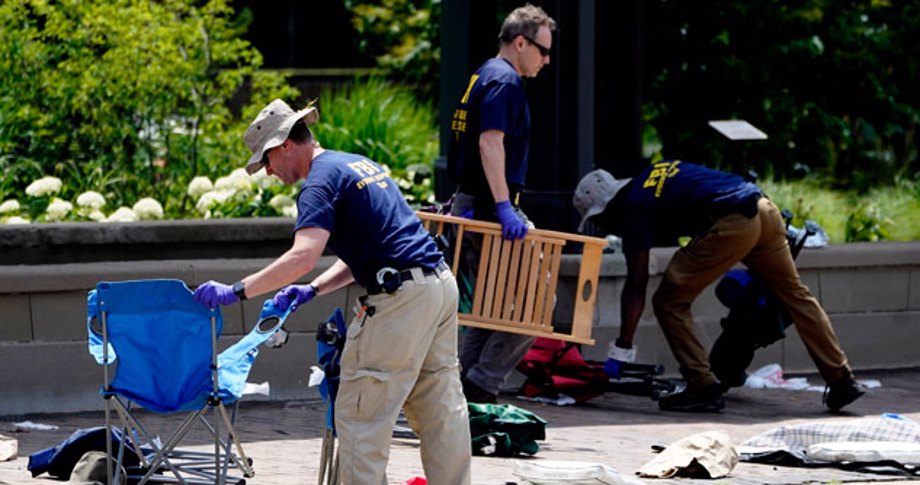 Men in blue T-shirts and purple gloves clean up debris after parade shooting