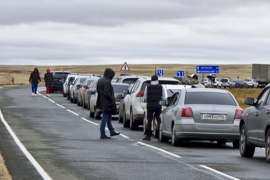 People walk next to their cars queuing to cross the border into Kazakhstan 