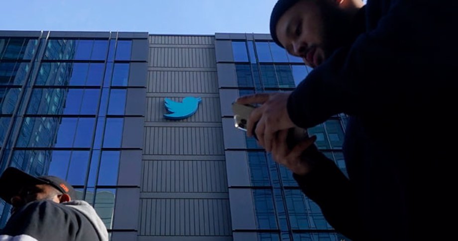 Man walking by Twitter headquarters texting on phone