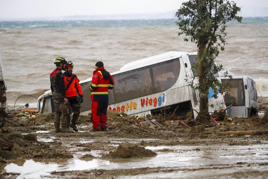 Rescuers stand next to a bus carried away after heavy rainfall triggered landslides that collapsed buildings and left as many as 12 people missing, in Casamicciola, on the southern Italian island of Ischia, Italy