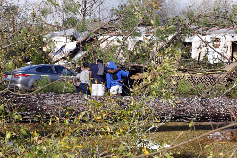 Friends and family pray outside a damaged mobile home, Wednesday, Nov. 30, 2022, in Flatwood, Ala., the day after a severe storm swept through the area. Two people were killed in the Flatwood community just north of the city of Montgomery.