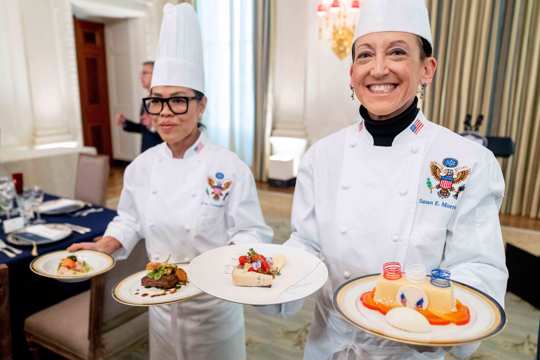 White House executive chef Cris Comerford, left, and White House executive pastry chef Susie Morrison, right, hold dishes during a media preview for the State Dinner with President Joe Biden and French President Emmanuel Macron in the State Dining Room of the White House in Washington, Wednesday, Nov. 30, 2022.