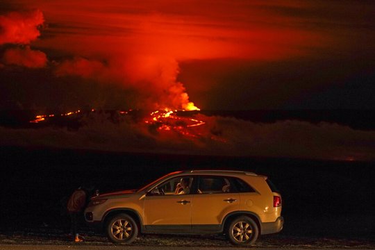 A man talks on a phone in his car alongside Saddle Road as the Mauna Loa volcano erupts. 