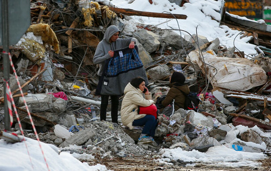 Family sits beside their collapsed home in Turkey