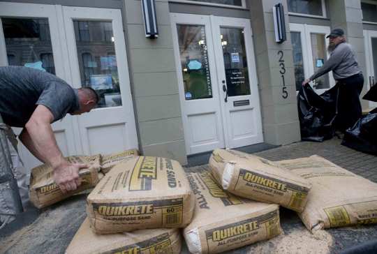 Jeremy Franklin, left, with Mitchell Historic Properties, unloads bags of sand at Texas Scuba Adventures, in Galveston, Texas