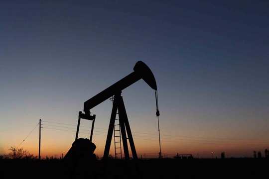 An oil derrick pump jack operates in an oil field in the Permian Basin in Texas