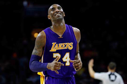 Los Angeles Lakers' Kobe Bryant smiles as he jogs to the bench during the first half of an NBA basketball game against the Philadelphia 76ers in Philadelphia