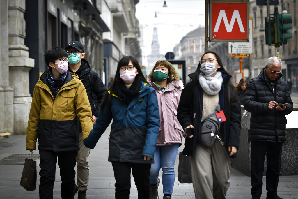 People wear sanitary masks as they walk in downtown Milan, Italy