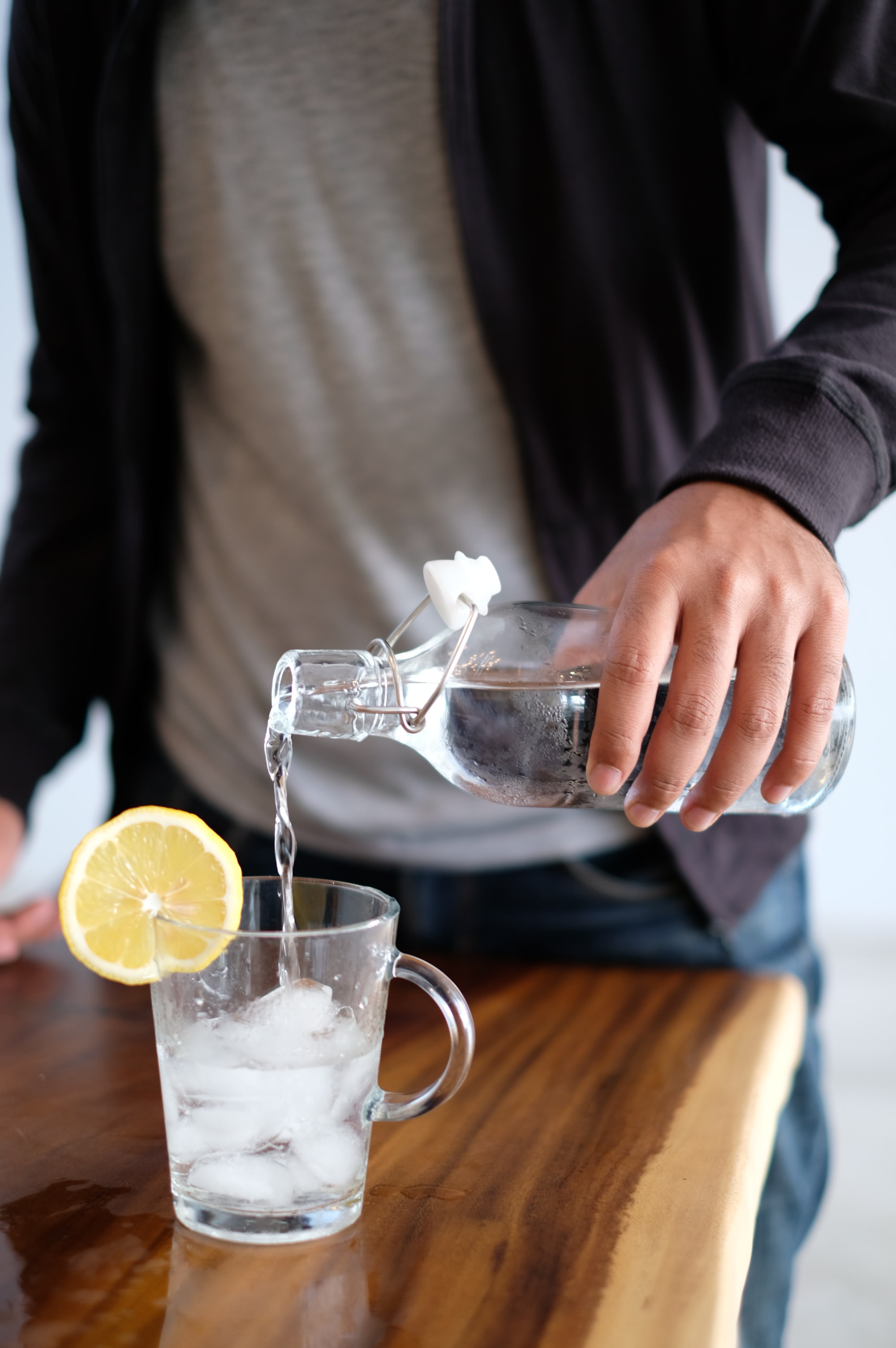 Man pouring water over ice, lemon slice on side