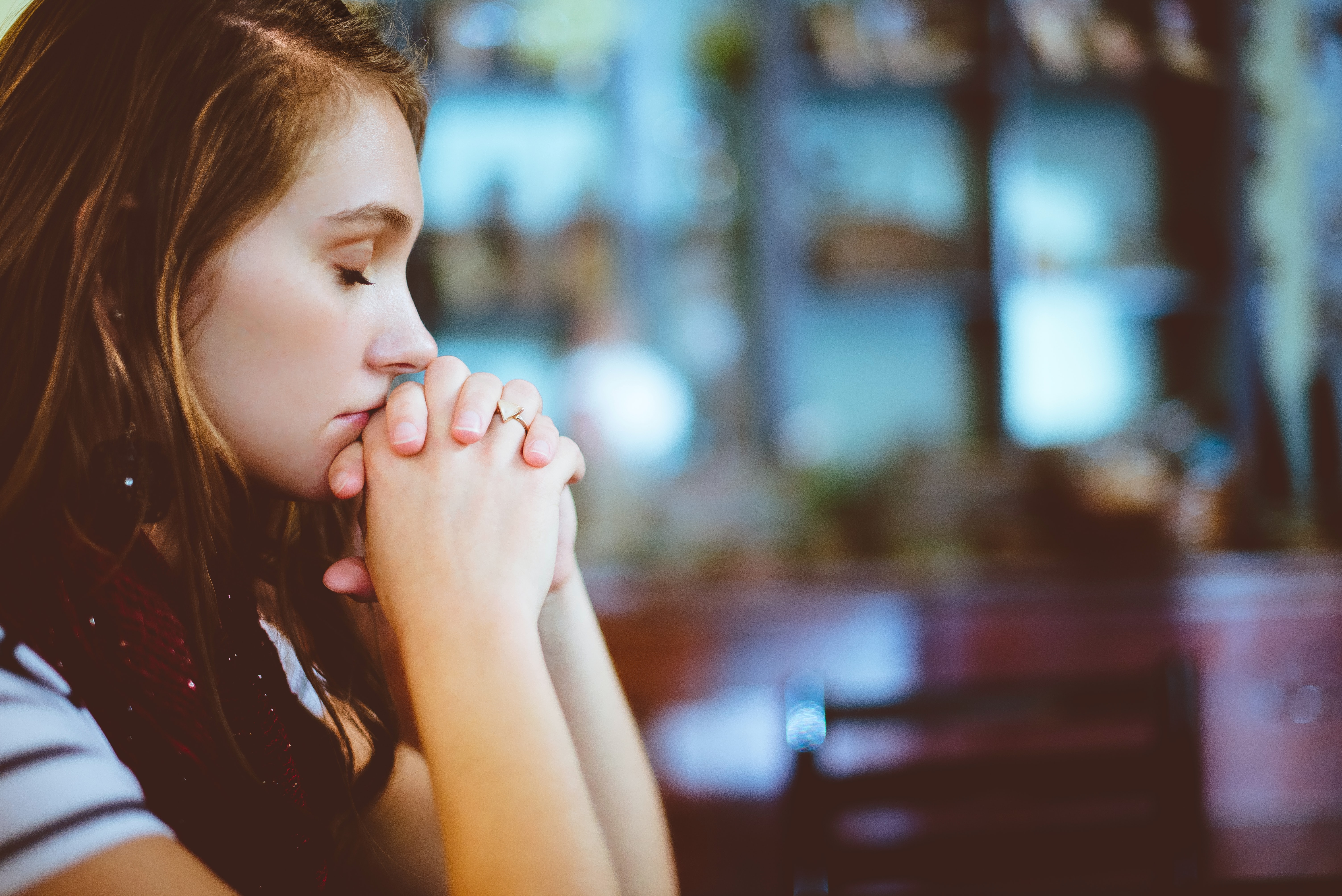 Woman praying, head bowed, chin on hands