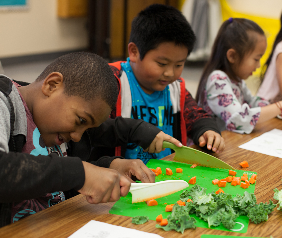 Kids chopping vegetables in classroom setting