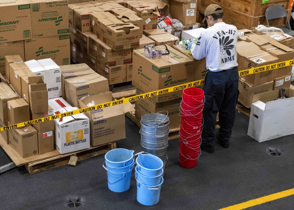 U.S. Navy Yeoman 2nd Class Ryan Snortland, of Wildomar, Calif., assembles buckets of sanitizer for Sailors disinfecting the aircraft carrier USS Theodore Roosevelt (CVN 71)