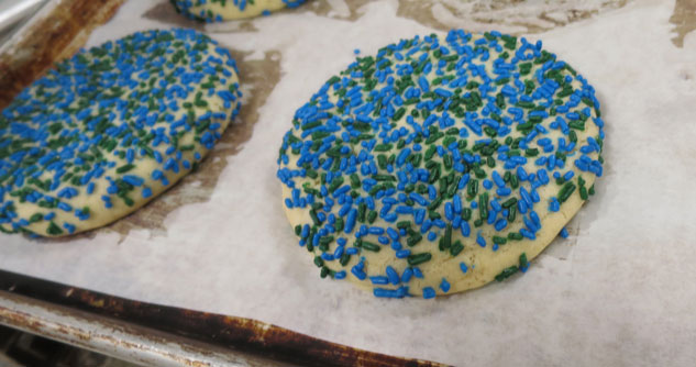 sugar cookies with blue and green sprinkles on waxed paper