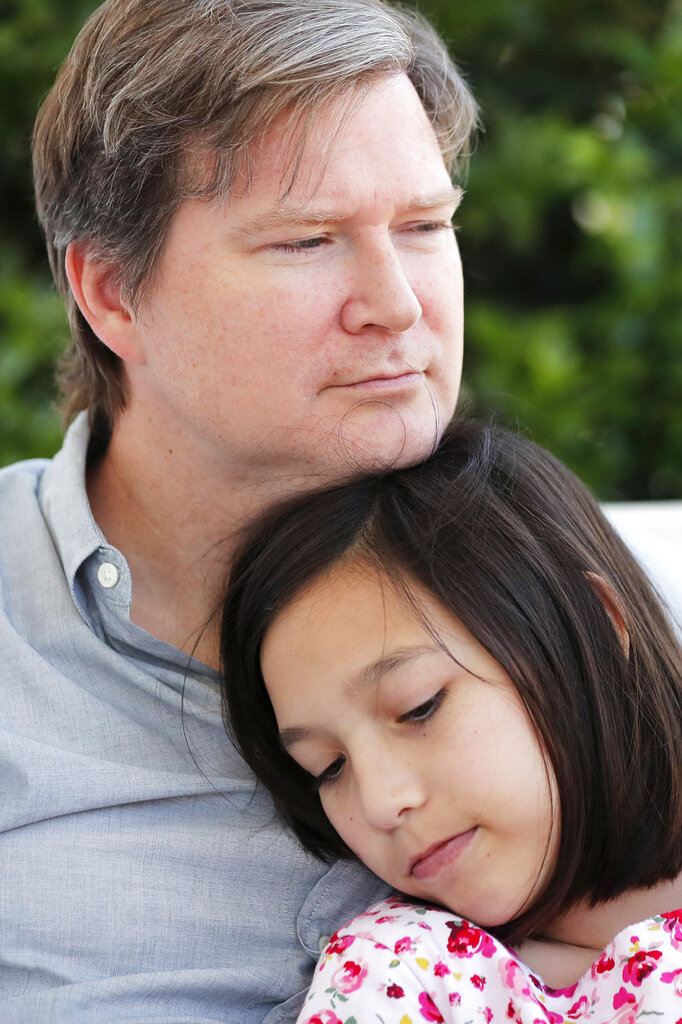 Juliet Daly, 12, sits with her father Sean Daly on the front porch of their family home