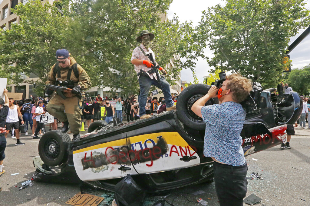 rmed protesters climb on a flipped over police vehicle Saturday, May 30, 2020, in Salt Lake City. Thousands of people converged on downtown Salt Lake City