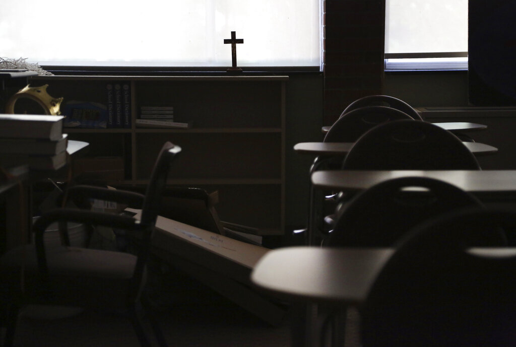 A cross sits in the window of an empty classroom at Quigley Catholic High School in Baden, Pa.