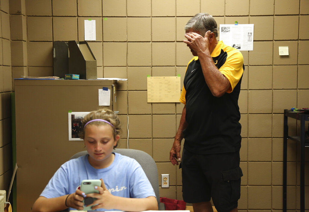 Cesa Pusateri, 12, accompanies her grandfather Timothy Waxenfelter, principal of Quigley Catholic High School, as he cleans out his office in Baden, Pa.,
