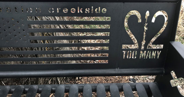 metal bench with Operation Creekside and 22 Too Many and American Flag carved out of bench